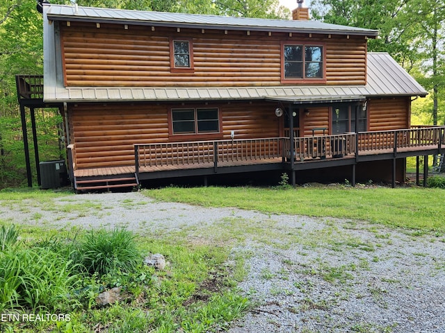 rear view of house with central AC unit, a chimney, a wooden deck, log veneer siding, and metal roof