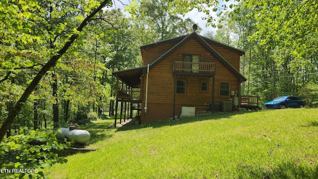 view of side of property with a yard, a balcony, and central air condition unit