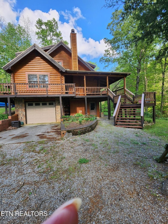 view of front of property featuring stairs, driveway, a chimney, a garage, and a deck