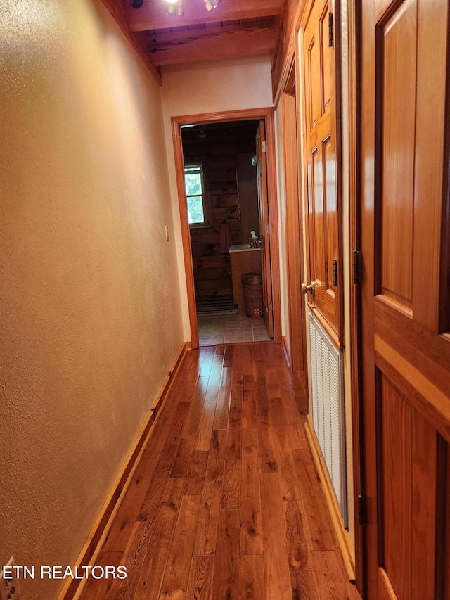 hall featuring hardwood / wood-style flooring, a textured wall, wood ceiling, and baseboards