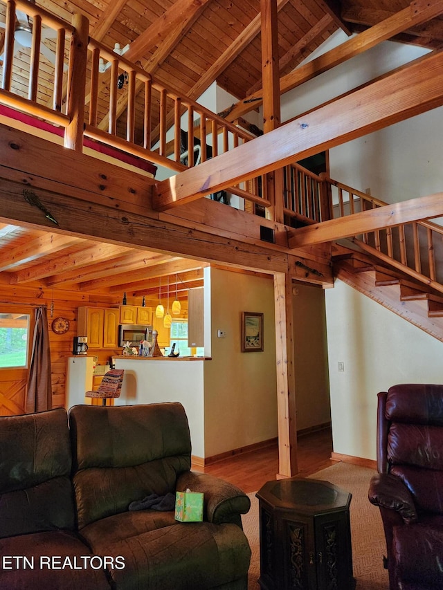 living room with stairway, beamed ceiling, high vaulted ceiling, baseboards, and wood finished floors