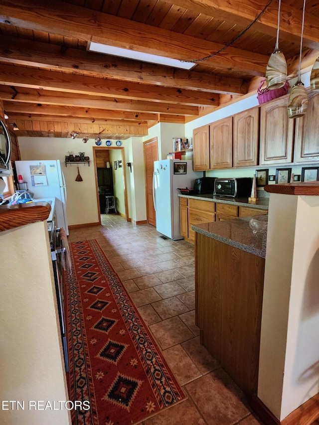 kitchen featuring baseboards, freestanding refrigerator, wood ceiling, dark countertops, and beamed ceiling