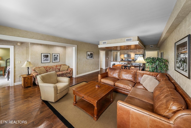 living area featuring dark wood finished floors, baseboards, and a textured wall
