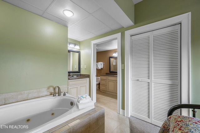 full bath featuring a whirlpool tub, vanity, tile patterned flooring, and a closet