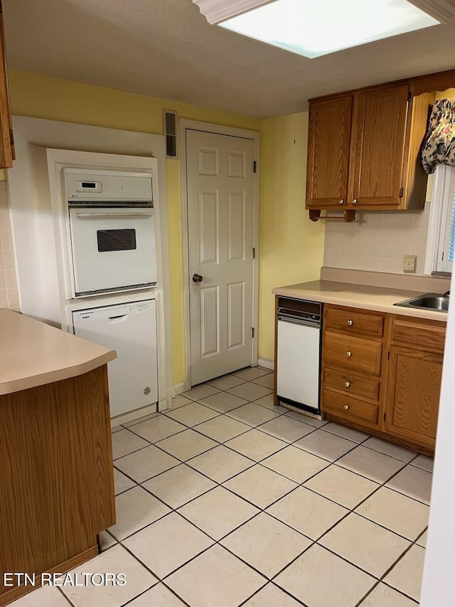 180 Cedar Ln, Jacksboro, TN 37757 - kitchen featuring white appliances, light countertops, brown cabinetry, light tile patterned flooring, and a sink