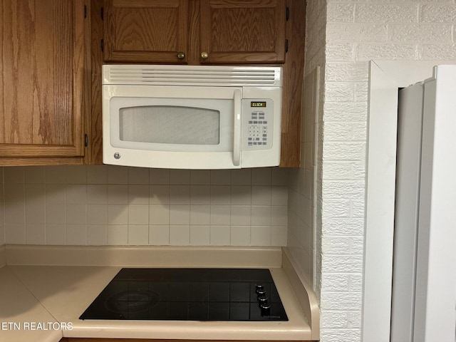 180 Cedar Ln, Jacksboro, TN 37757 - kitchen view of white microwave, black electric cooktop, tasteful backsplash, and light countertops