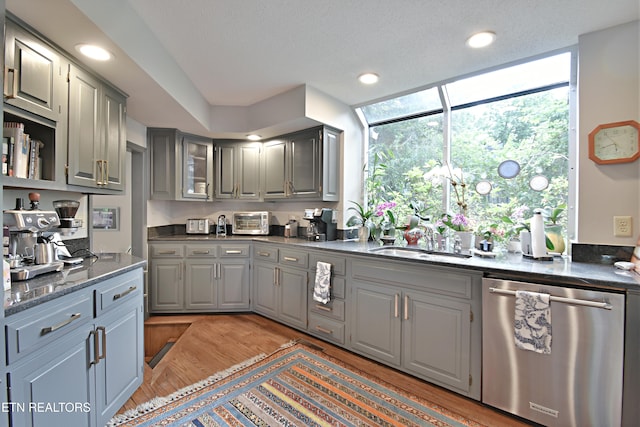 12212 Oakmont Cir, Knoxville, TN 37934 - kitchen featuring stainless steel dishwasher, gray cabinetry, a sink, light wood-type flooring, and glass insert cabinets