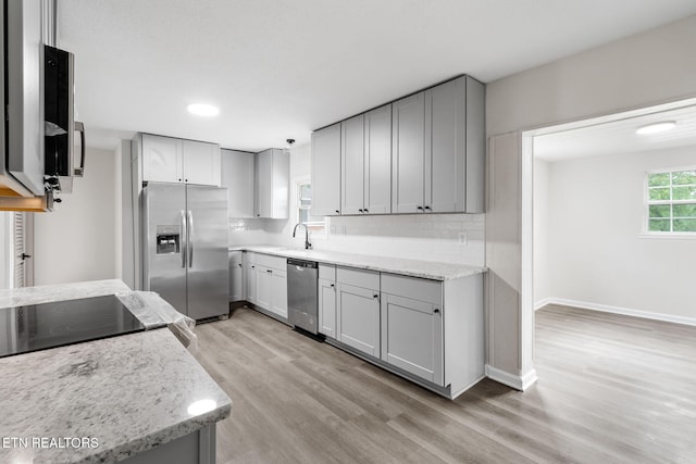 9505 Pearson Rd, Harrison, TN 37341 - kitchen with appliances with stainless steel finishes, light wood finished floors, light stone counters, decorative backsplash, and gray cabinets
