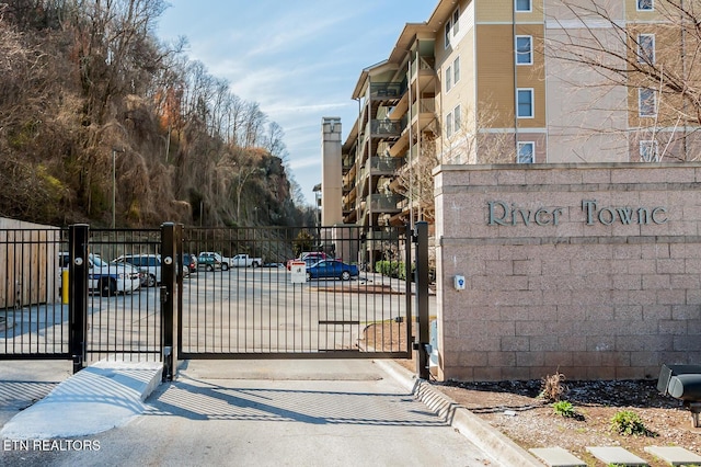 view of street with a gate, a gated entry, and curbs