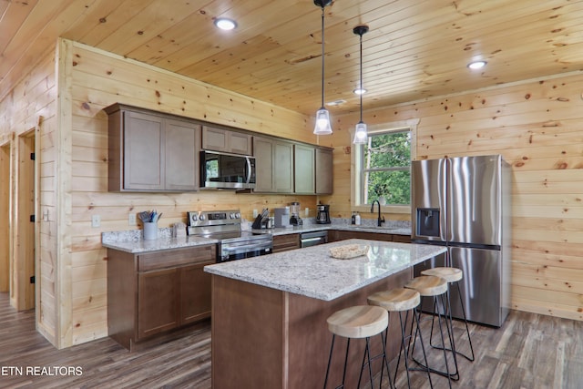 kitchen with appliances with stainless steel finishes, wooden ceiling, dark wood-type flooring, wooden walls, and a sink