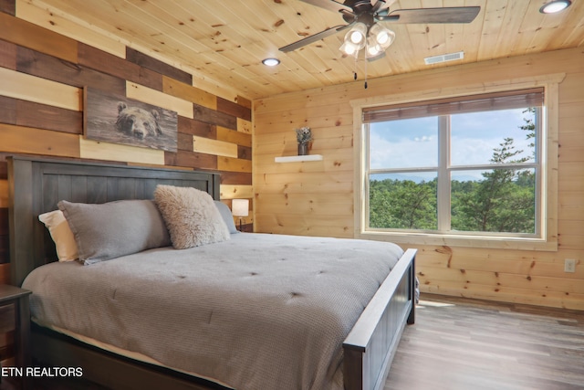 bedroom with wooden walls, wood ceiling, recessed lighting, and wood finished floors