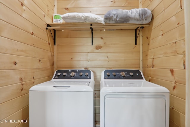 clothes washing area featuring washing machine and clothes dryer and wooden walls