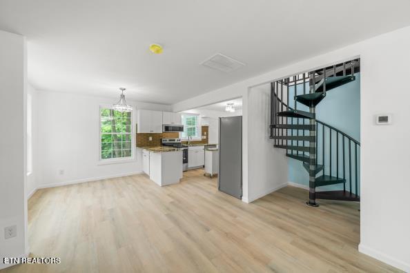 739 W Main St, Sevierville, TN 37862 - kitchen featuring stainless steel appliances, white cabinets, light wood finished floors, baseboards, and pendant lighting