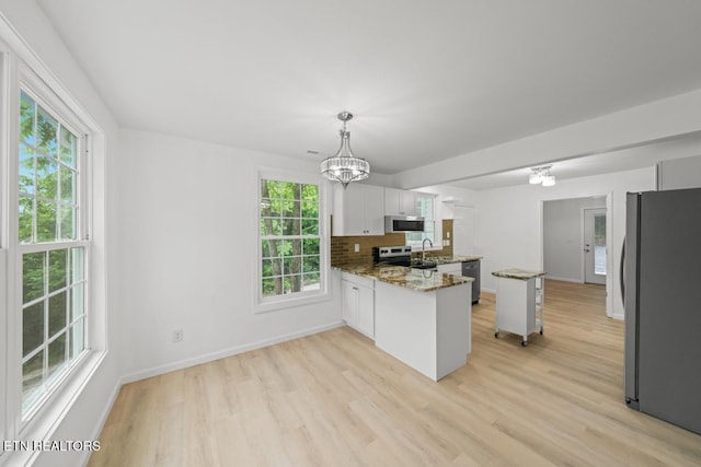 739 W Main St, Sevierville, TN 37862 - kitchen with stainless steel appliances, a chandelier, a peninsula, and light wood-type flooring