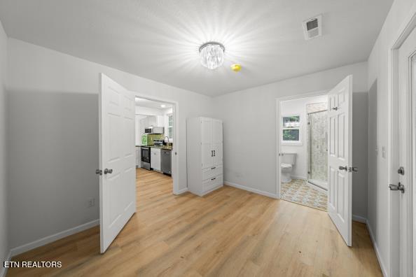 739 W Main St, Sevierville, TN 37862 - unfurnished bedroom with light wood-style floors, baseboards, and ensuite bathroom