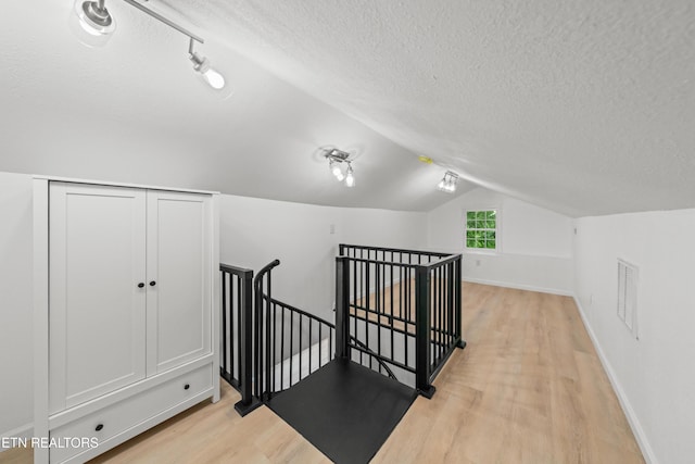 739 W Main St, Sevierville, TN 37862 - additional living space with light wood-style floors, a textured ceiling, vaulted ceiling, and baseboards