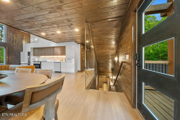 dining room featuring wooden ceiling, wood walls, and light wood-type flooring