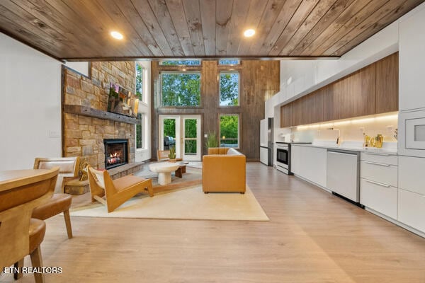 living area featuring wood ceiling, a fireplace, light wood-type flooring, recessed lighting, and a high ceiling