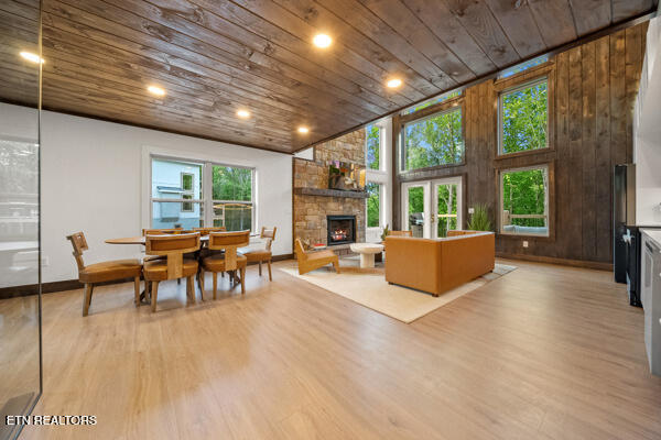 living area with wood ceiling, a stone fireplace, light wood finished floors, and recessed lighting