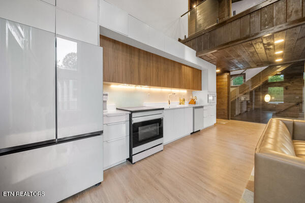 kitchen featuring freestanding refrigerator, range with electric stovetop, dishwasher, and modern cabinets
