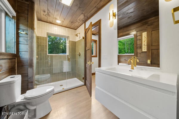 bathroom featuring wood ceiling, toilet, plenty of natural light, a stall shower, and wood finished floors