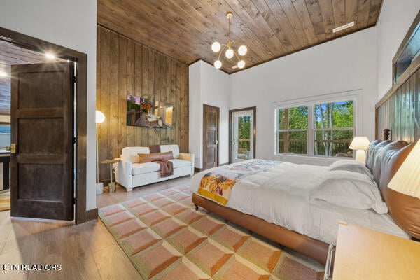 bedroom with high vaulted ceiling, wood ceiling, a chandelier, wood finished floors, and wooden walls
