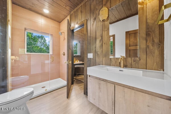 bathroom with wood ceiling, toilet, a shower stall, wood finished floors, and vanity