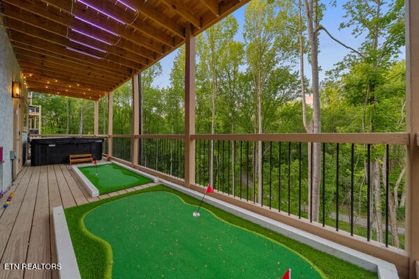 deck featuring a putting area and a hot tub