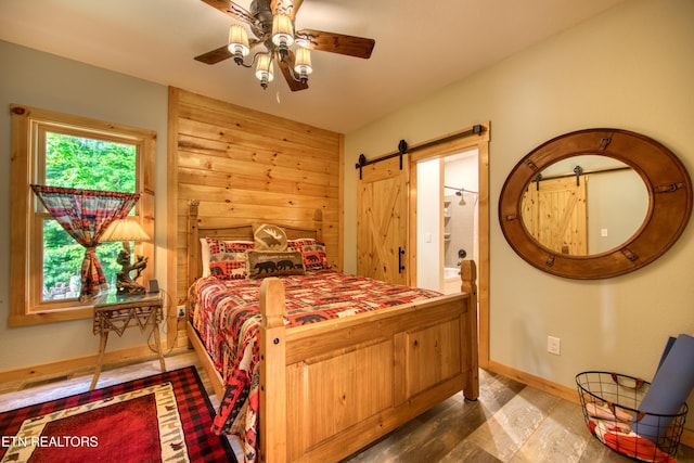 305 Griffin Ln, Allardt, TN 38504 - bedroom with a barn door, wood finished floors, baseboards, ensuite bathroom, and a ceiling fan