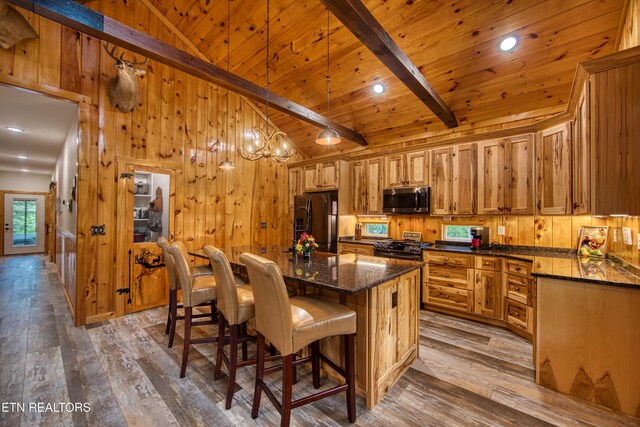 305 Griffin Ln, Allardt, TN 38504 - kitchen featuring black appliances, hardwood / wood-style flooring, wooden walls, a breakfast bar area, and a kitchen island