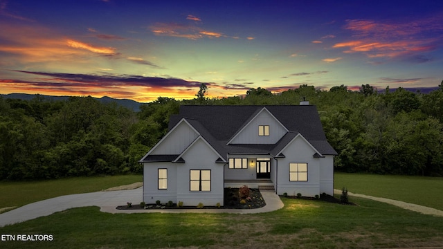 modern farmhouse style home featuring a front yard, roof with shingles, and a chimney