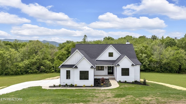 modern farmhouse style home featuring covered porch, a front lawn, board and batten siding, and a chimney