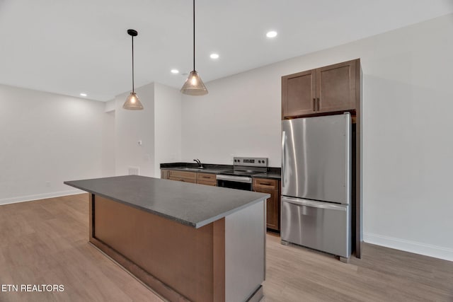 kitchen with stainless steel appliances, dark countertops, light wood-style floors, a sink, and recessed lighting