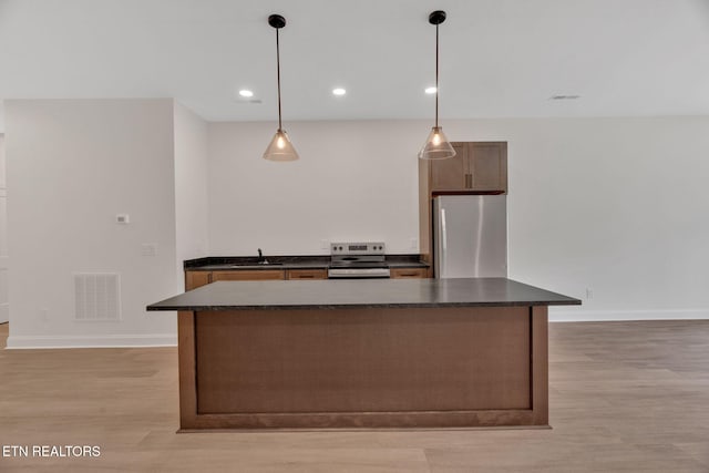 kitchen with stainless steel appliances, dark countertops, light wood-type flooring, a sink, and recessed lighting