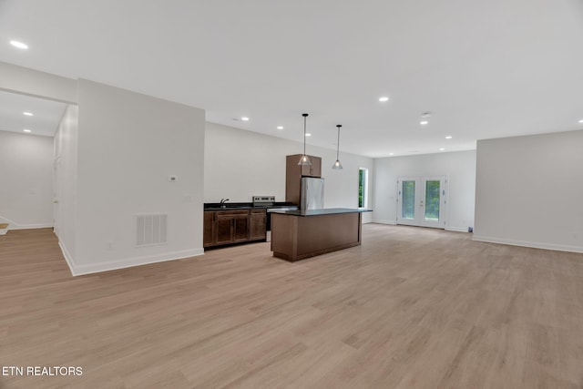 kitchen with freestanding refrigerator, open floor plan, recessed lighting, light wood-style flooring, and baseboards
