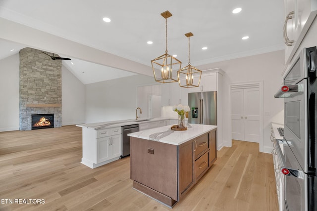 kitchen featuring appliances with stainless steel finishes, white cabinetry, a peninsula, open floor plan, and lofted ceiling