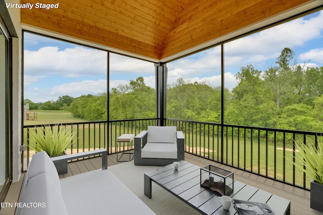 sunroom featuring lofted ceiling, an outdoor hangout area, and a view of trees