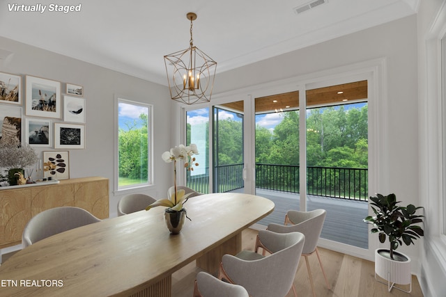 dining space featuring a chandelier, healthy amount of natural light, light wood-style floors, and ornamental molding