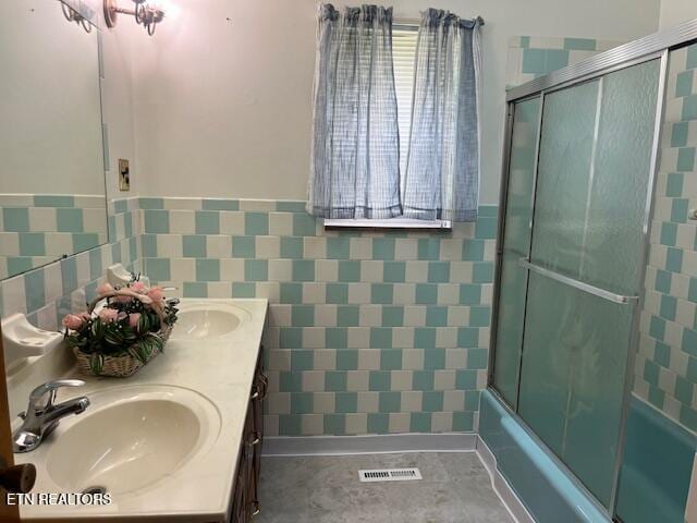 1634 Snodderly Dr, Lenoir City, TN 37771 - bathroom featuring tile walls, double vanity, shower / bath combination with glass door, and a wainscoted wall