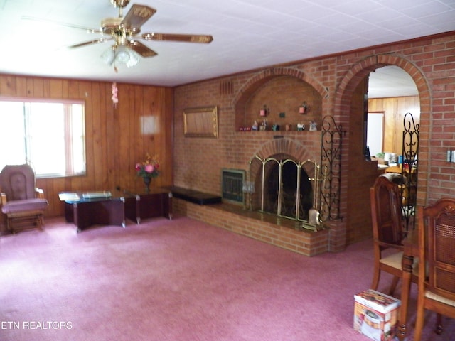 1634 Snodderly Dr, Lenoir City, TN 37771 - living area featuring carpet floors, a fireplace, ceiling fan, wood walls, and arched walkways