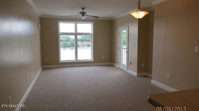 empty room with ceiling fan, crown molding, carpet floors, healthy amount of natural light, and baseboards