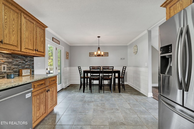 1023 NE Old Charleston Rd, Cleveland, TN 37312 - kitchen with stainless steel appliances, a wainscoted wall, a textured ceiling, brown cabinets, and crown molding