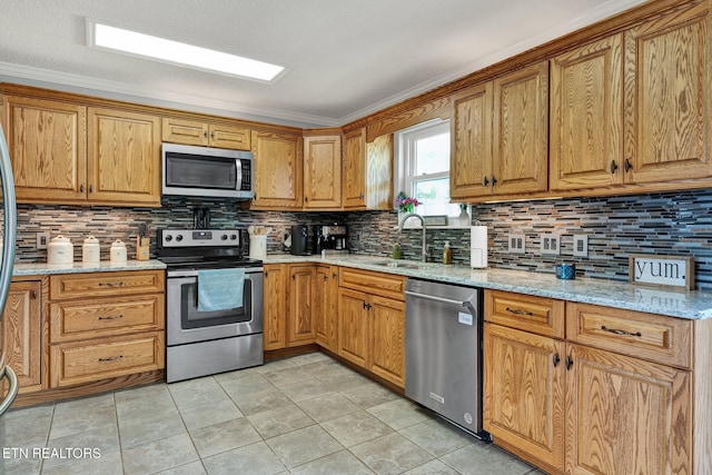 1023 NE Old Charleston Rd, Cleveland, TN 37312 - kitchen featuring appliances with stainless steel finishes, a sink, tasteful backsplash, light stone counters, and ornamental molding