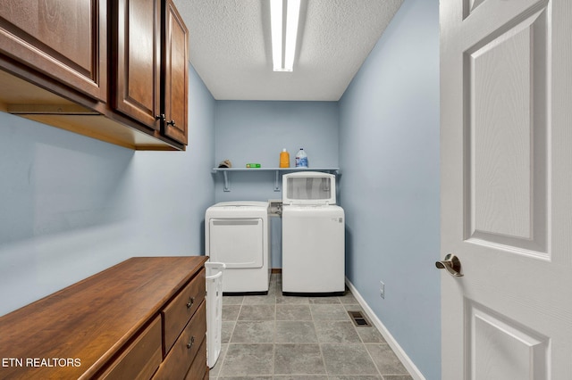 1023 NE Old Charleston Rd, Cleveland, TN 37312 - laundry room featuring independent washer and dryer, cabinet space, baseboards, a textured ceiling, and light stone finish flooring