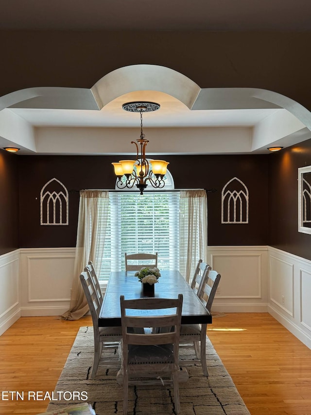 900 Twin Fawn Trl, Middlesboro, KY 40965 - dining room featuring arched walkways, light wood finished floors, a chandelier, a decorative wall, and a wainscoted wall