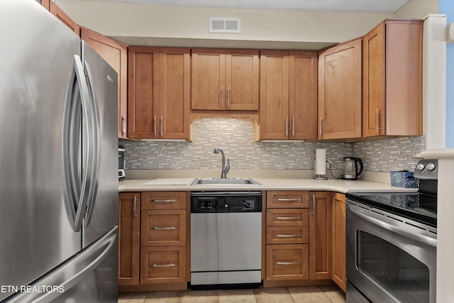 kitchen featuring stainless steel appliances, a sink, light countertops, and light tile patterned flooring