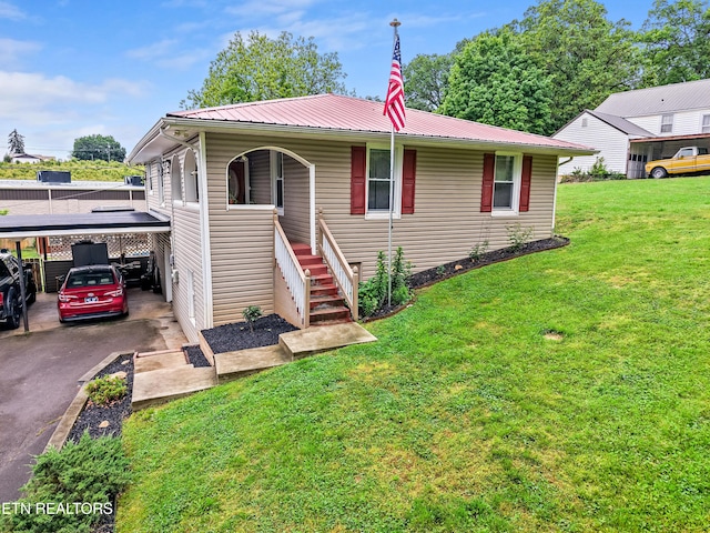 ranch-style house with a carport, a porch, a front yard, metal roof, and asphalt driveway
