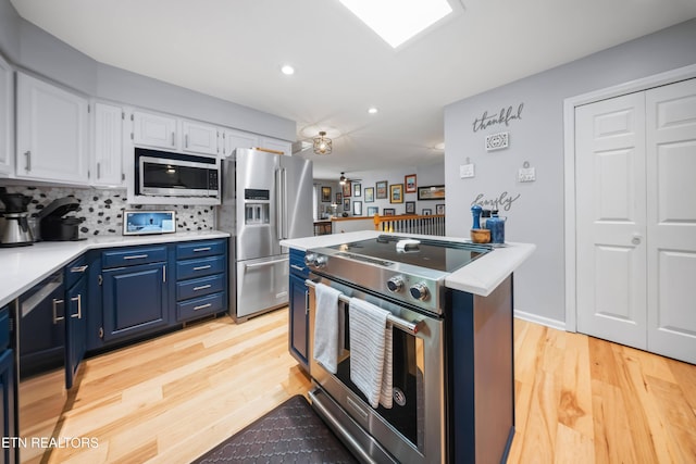 118 Motthaven Dr, Crossville, TN 38558 - kitchen with appliances with stainless steel finishes, blue cabinetry, light countertops, white cabinetry, and light wood finished floors