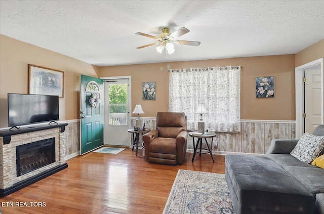 138 Robinson Ln, Middlesboro, KY 40965 - living area featuring a wainscoted wall, a ceiling fan, wood finished floors, a textured ceiling, and a stone fireplace