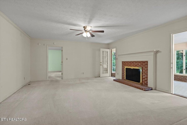unfurnished living room featuring ornamental molding, ceiling fan, carpet flooring, a brick fireplace, and a textured ceiling
